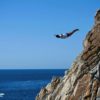 A cliff diver leaps from the rocks above Acapulco after the Mexican resort allowed resumption of the activity in the aftermath of deadly Hurricane Otis, but tourists are only slowly returning to the region