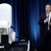 Elon Musk standing next to a surgical robot during a Neuralink presentation in 2020