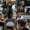 A couple pose for photos next to the statue of 'Hachiko' in front of Tokyo's Shibuya station