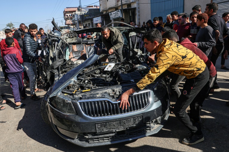 Crowds examine the car in which two journalists, Mustafa Thuria, a video stringer for AFP news agency, and Hamza Wael Dahdouh, a journalist with Al Jazeera television network, were killed in an air strike on Rafah blamed by Hamas on Israel