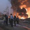 People are seen in front of flames from the fire at Conakry's main fuel depot on December 18, 2023