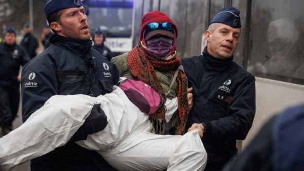 Police officers detain an environmental activist of the Code Red coalition during a demonstration against the aviation industry in Antwerp